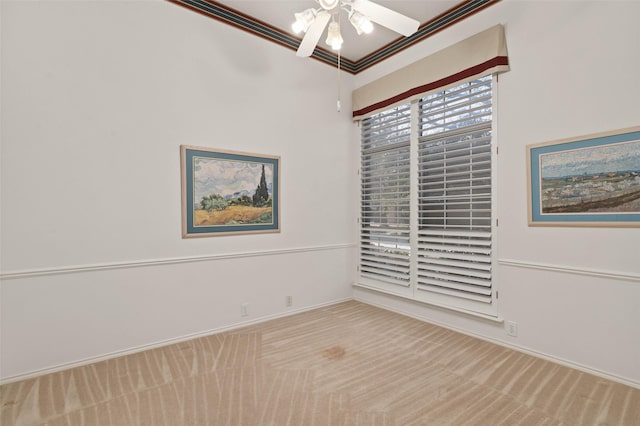 carpeted spare room with a ceiling fan, baseboards, and ornamental molding