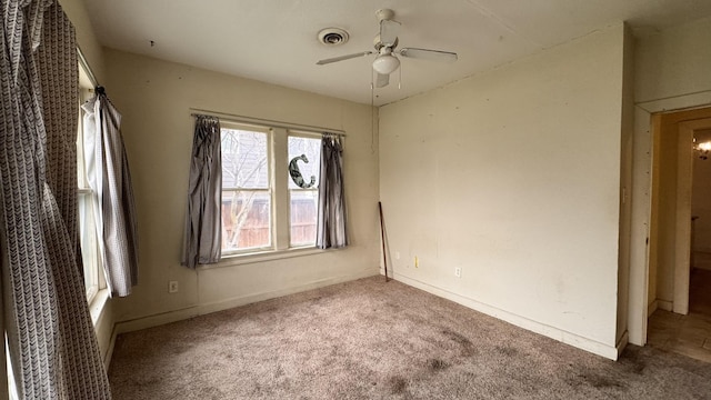 carpeted spare room featuring baseboards, visible vents, and a ceiling fan