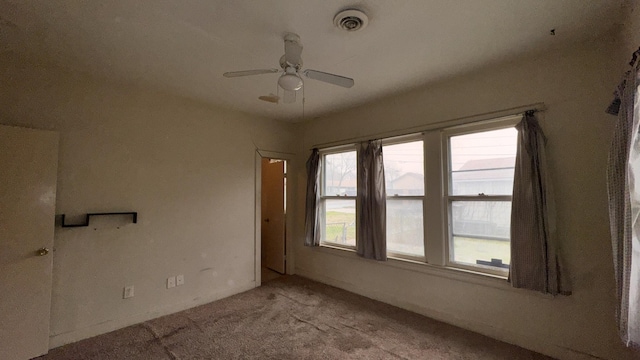 carpeted spare room with visible vents and a ceiling fan