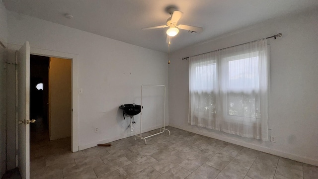 spare room featuring a ceiling fan and baseboards