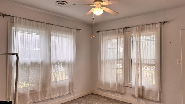 spare room featuring a ceiling fan, a healthy amount of sunlight, visible vents, and baseboards