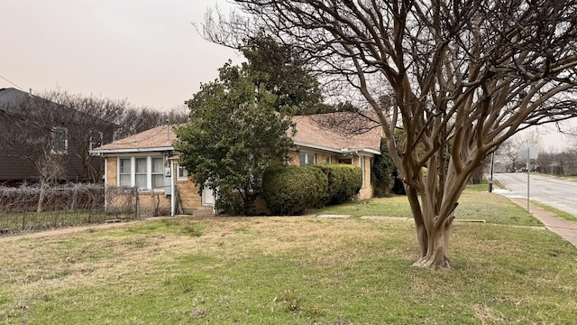 view of front facade with brick siding, fence, and a front lawn