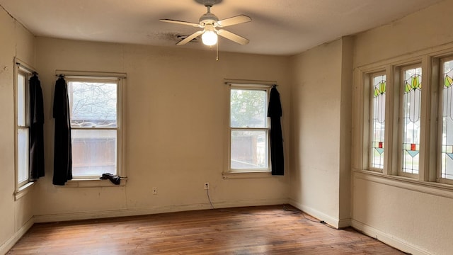 empty room with light wood finished floors, a ceiling fan, and a healthy amount of sunlight