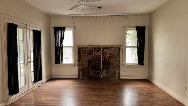 unfurnished living room featuring baseboards, wood finished floors, and a stone fireplace