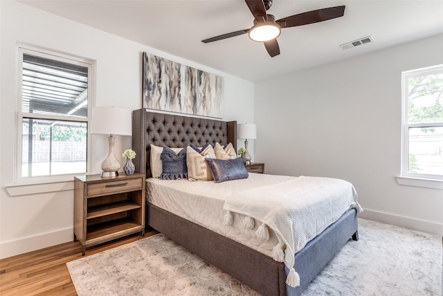 bedroom featuring a ceiling fan, baseboards, visible vents, and wood finished floors