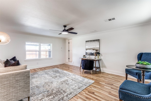 sitting room featuring baseboards, visible vents, wood finished floors, and ornamental molding