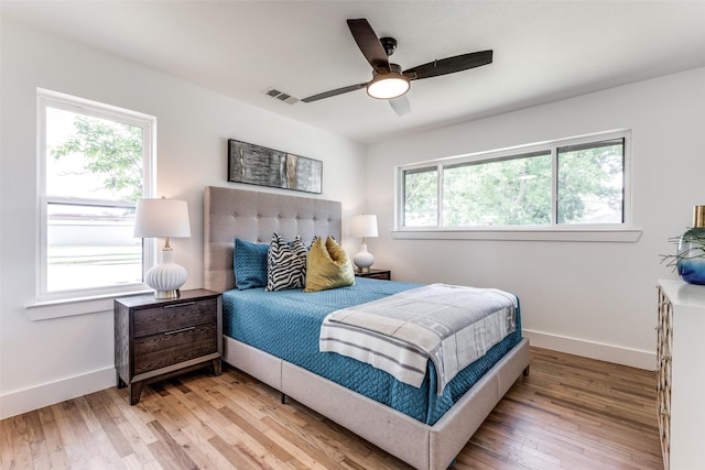 bedroom featuring ceiling fan, light wood-type flooring, visible vents, and baseboards