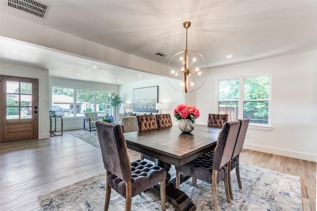 dining space with light wood-style flooring, visible vents, a chandelier, and baseboards