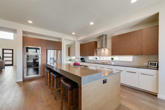 3743 Pistol Creek Dr, Frisco, TX 75034 - kitchen featuring wall chimney exhaust hood, stainless steel appliances, modern cabinets, a sink, and a breakfast bar