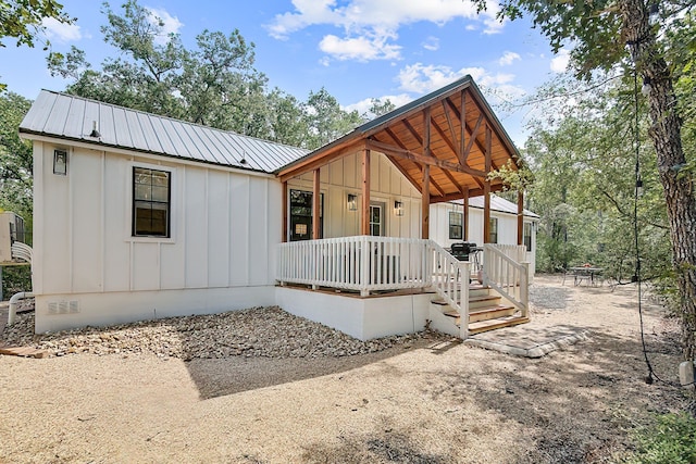 view of front of property featuring crawl space, covered porch, metal roof, and board and batten siding