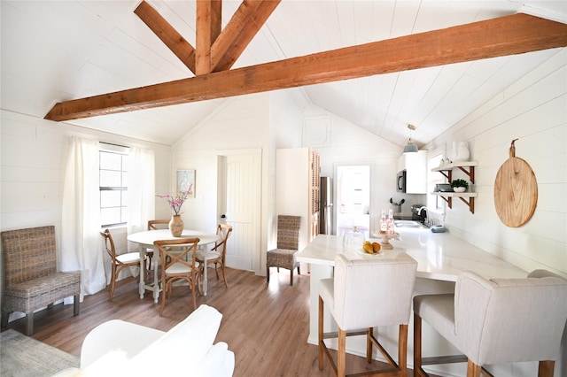 dining room featuring vaulted ceiling with beams and light wood-style flooring
