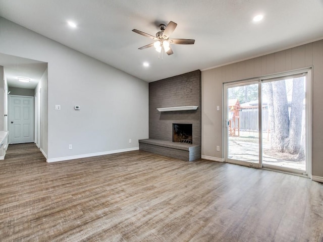 unfurnished living room featuring a fireplace, wood finished floors, a ceiling fan, and baseboards