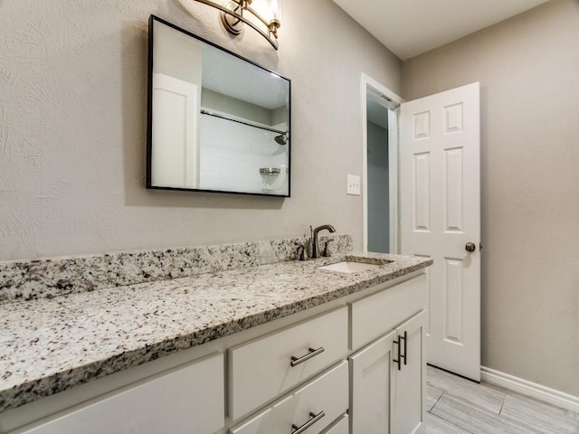 bathroom with wood tiled floor, walk in shower, vanity, and baseboards