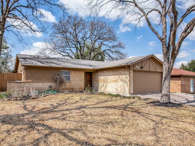 view of front of home with brick siding, concrete driveway, a front yard, fence, and a garage