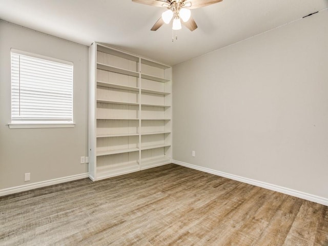 empty room with a ceiling fan, baseboards, and wood finished floors