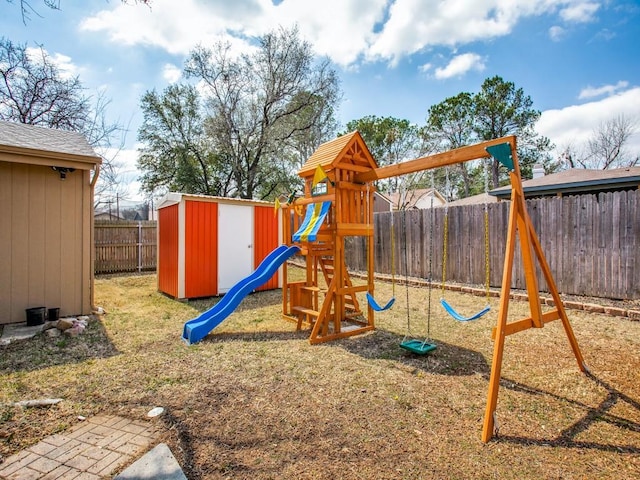 view of playground featuring a fenced backyard, a shed, and an outbuilding