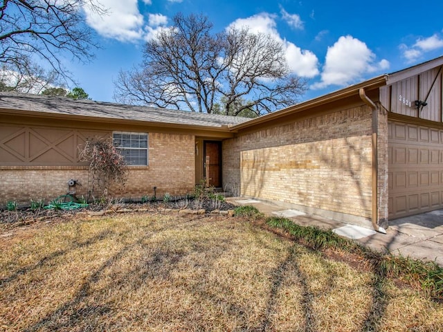 exterior space featuring a garage, brick siding, and a yard