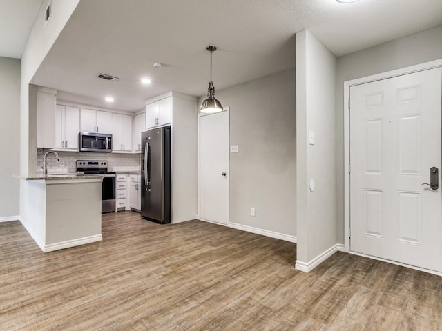 kitchen featuring visible vents, appliances with stainless steel finishes, backsplash, light wood-type flooring, and a sink