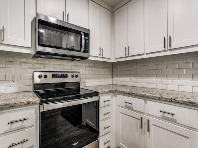 kitchen featuring light stone counters, appliances with stainless steel finishes, white cabinets, and tasteful backsplash