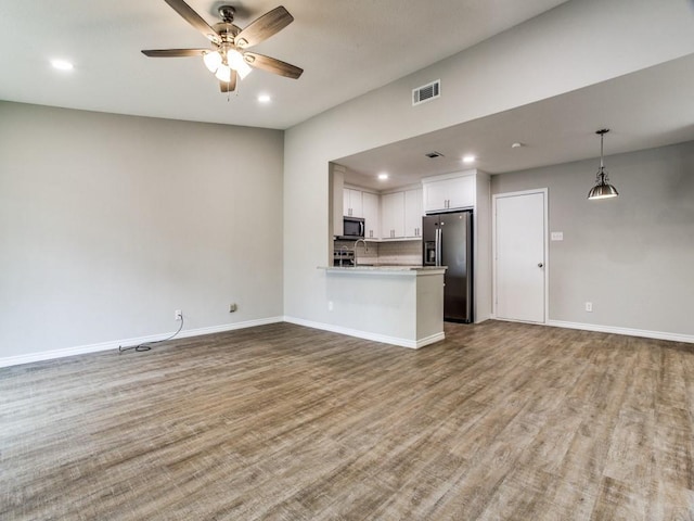 unfurnished living room featuring wood finished floors, visible vents, and baseboards