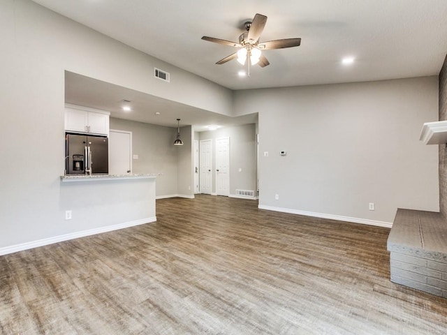 unfurnished living room with baseboards, visible vents, and wood finished floors