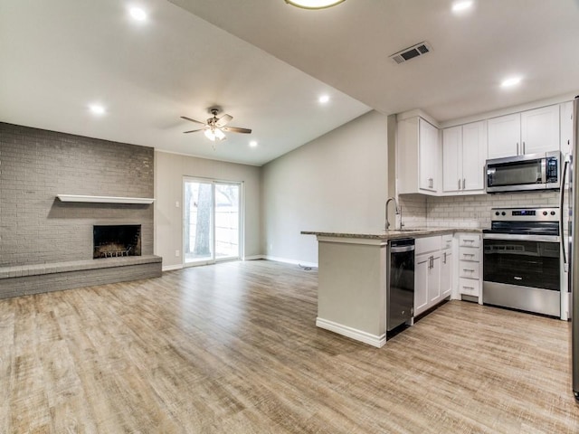 kitchen with visible vents, white cabinets, light wood-style flooring, appliances with stainless steel finishes, and a peninsula