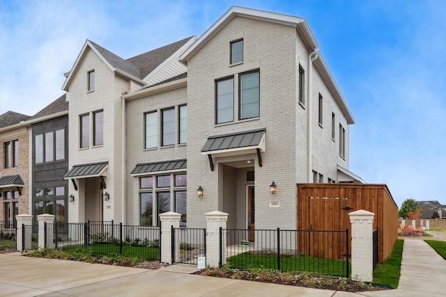 multi unit property featuring a fenced front yard, a standing seam roof, brick siding, and metal roof