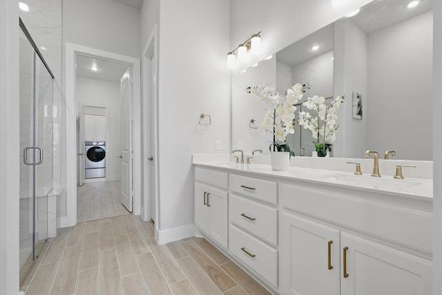 full bath with washer / dryer, wood finish floors, a sink, and a shower stall