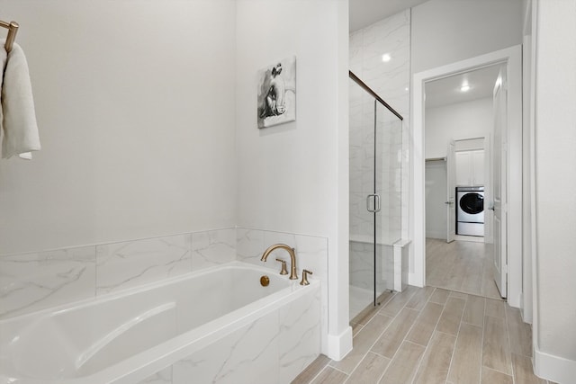 full bathroom with a garden tub, washer / clothes dryer, a shower stall, and wood tiled floor