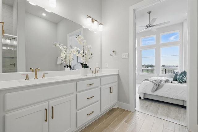 ensuite bathroom with a ceiling fan, wood finish floors, a sink, and double vanity