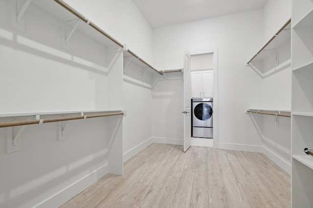 walk in closet with washer / dryer and light wood-style floors