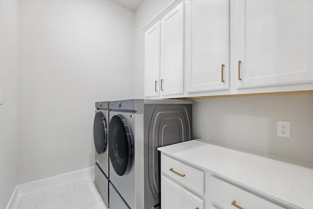 clothes washing area featuring cabinet space, baseboards, marble finish floor, and washer and dryer