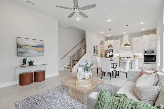 living area with light wood-type flooring, recessed lighting, visible vents, and stairs