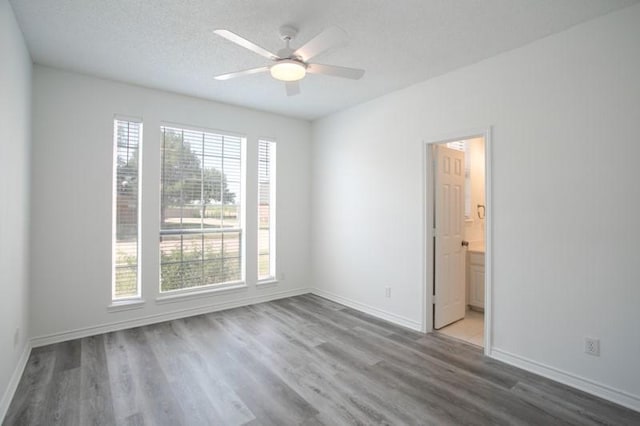 spare room with ceiling fan, a textured ceiling, baseboards, and wood finished floors