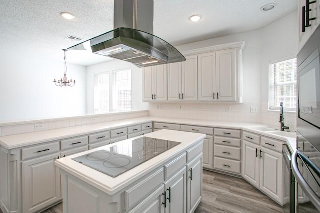 kitchen with black electric cooktop, island range hood, a sink, a kitchen island, and a wealth of natural light