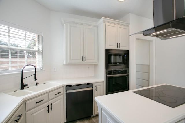 kitchen featuring dishwashing machine, oven, black electric cooktop, a sink, and wall chimney range hood