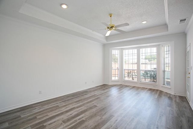 empty room with a textured ceiling, a raised ceiling, and crown molding