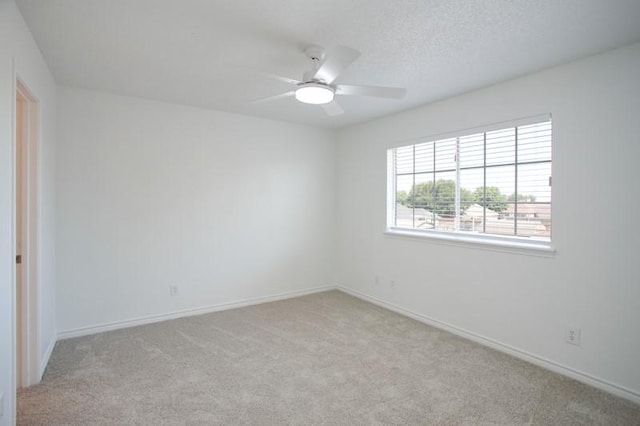 unfurnished room with carpet floors, ceiling fan, baseboards, and a textured ceiling