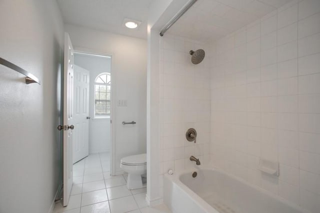 bathroom with shower / bath combination, tile patterned flooring, toilet, and baseboards