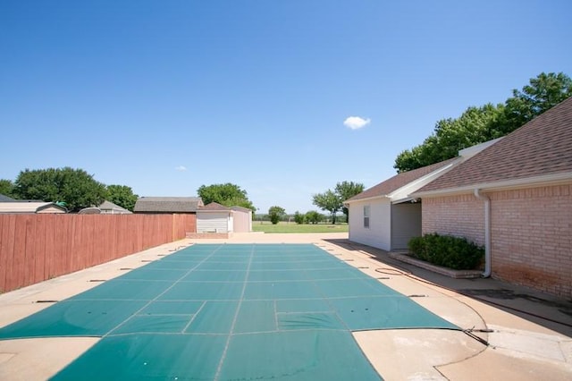 view of swimming pool with a fenced in pool, a patio, fence, an outdoor structure, and a shed