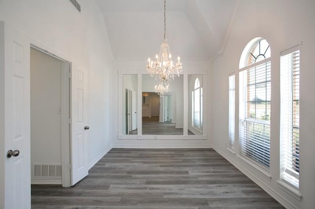 unfurnished dining area featuring wood finished floors, visible vents, and a notable chandelier