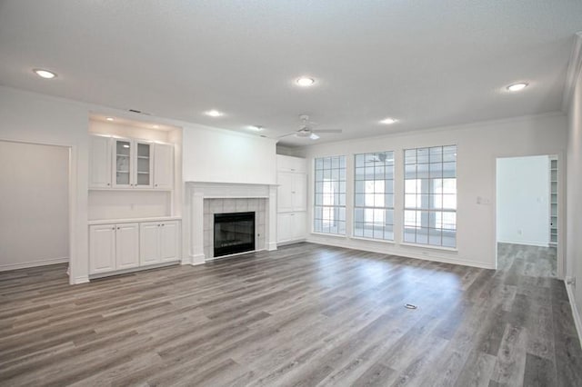 unfurnished living room featuring a tile fireplace, recessed lighting, wood finished floors, and baseboards