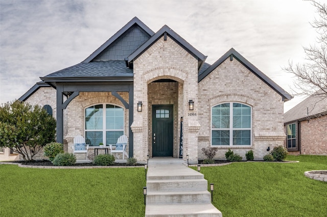 french provincial home with a shingled roof, brick siding, and a front lawn