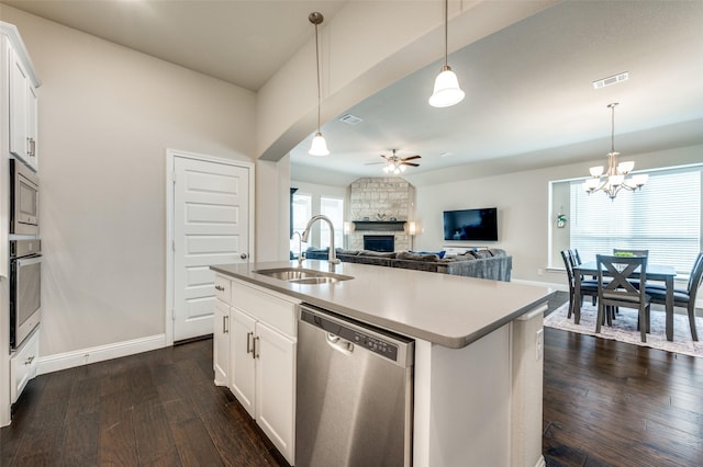 kitchen featuring dark wood-style flooring, a fireplace, appliances with stainless steel finishes, a sink, and ceiling fan with notable chandelier