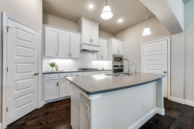 kitchen featuring premium range hood, a sink, stainless steel microwave, dark wood finished floors, and an island with sink