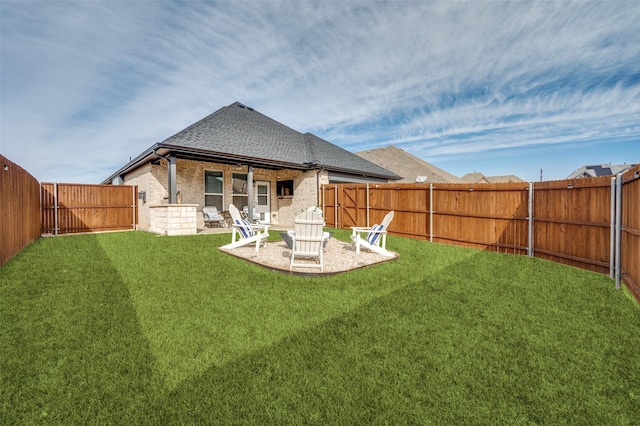 back of property with a fenced backyard, brick siding, roof with shingles, a lawn, and a patio area