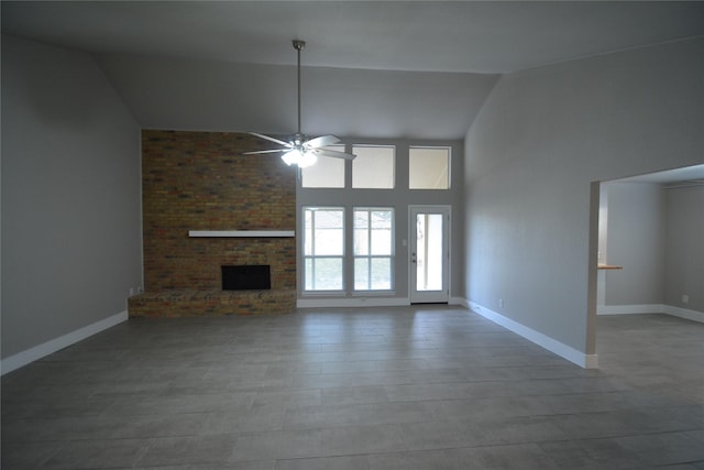 unfurnished living room with ceiling fan, high vaulted ceiling, a fireplace, and baseboards