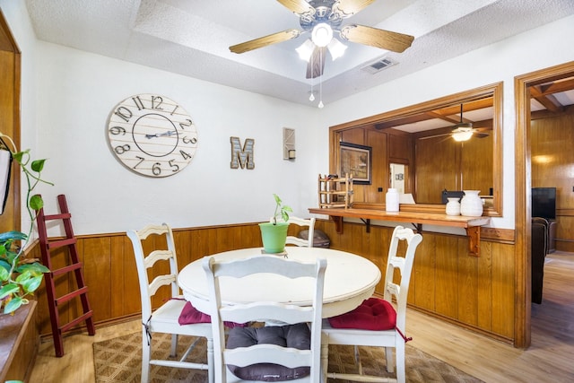 4017 Cherryhill Ct, Arlington, TX 76016 - dining room featuring a ceiling fan, light wood-type flooring, wood walls, and a wainscoted wall