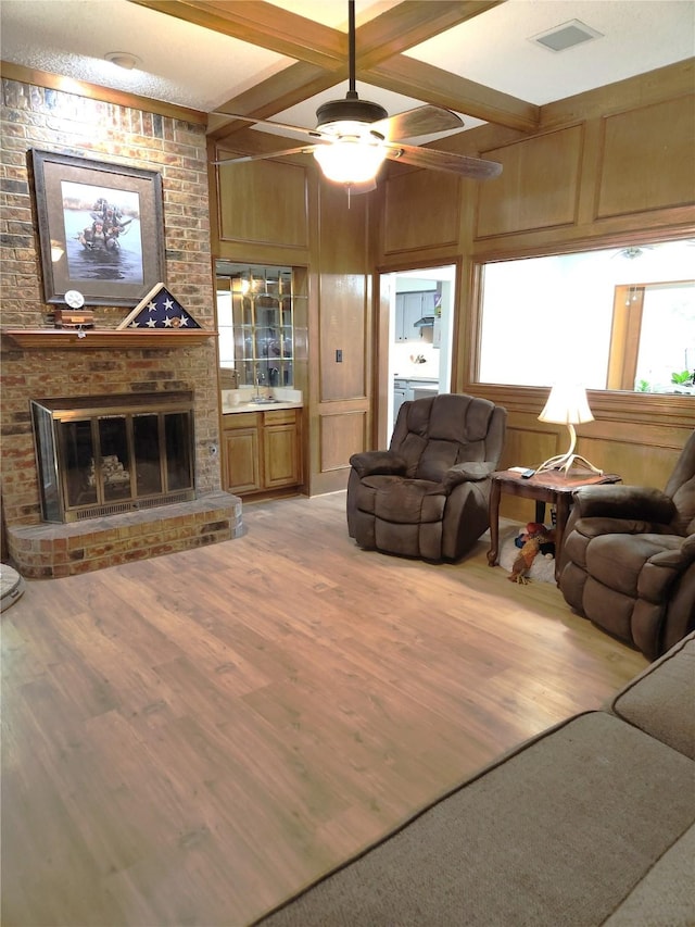 4017 Cherryhill Ct, Arlington, TX 76016 - living area featuring light wood-style floors, a brick fireplace, beam ceiling, a ceiling fan, and wood walls