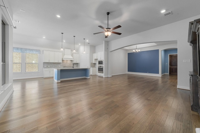 2121 Newton Ln, Mckinney, TX 75071 - unfurnished living room with arched walkways, recessed lighting, ceiling fan with notable chandelier, and dark wood-type flooring